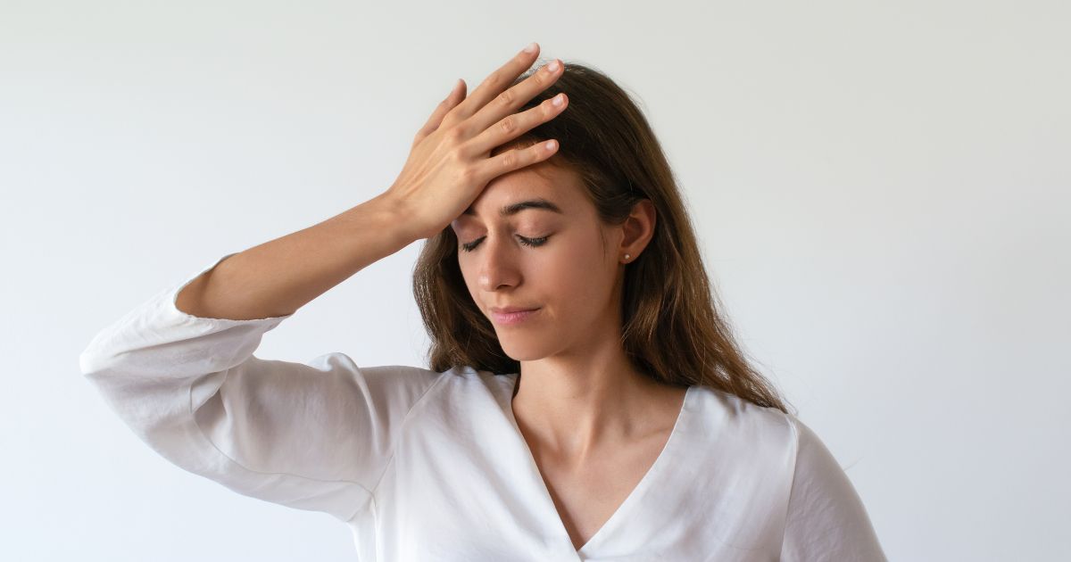 mulher jovem com uma das mãos sobre a testa e expressão de esquecimento